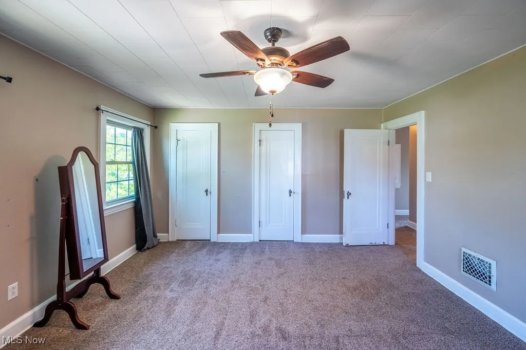 Unfurnished bedroom with multiple closets, carpet floors, and ceiling fan