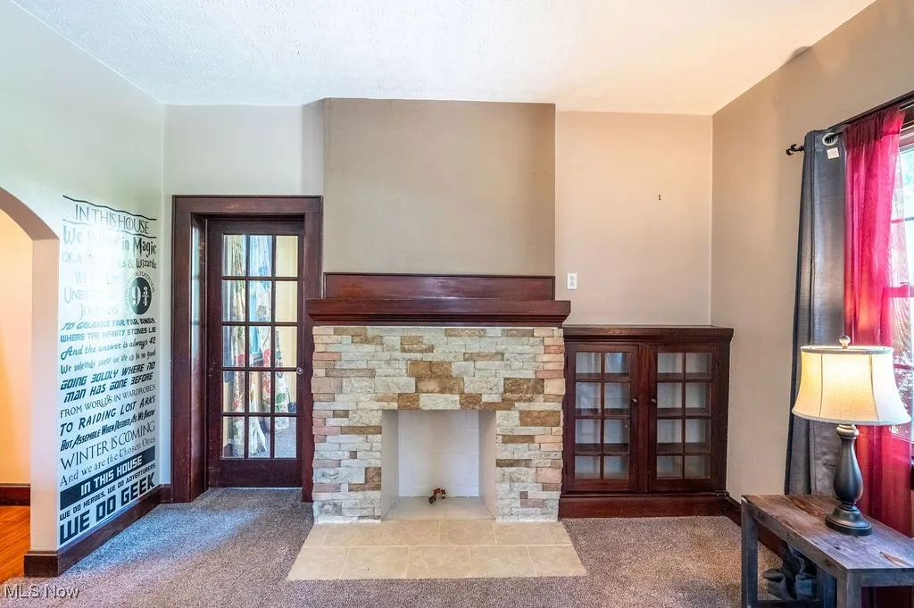 Living area featuring a fireplace, carpet flooring, and arched walkways
