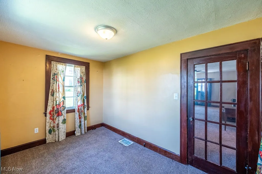 Carpeted spare room featuring baseboards and a textured ceiling