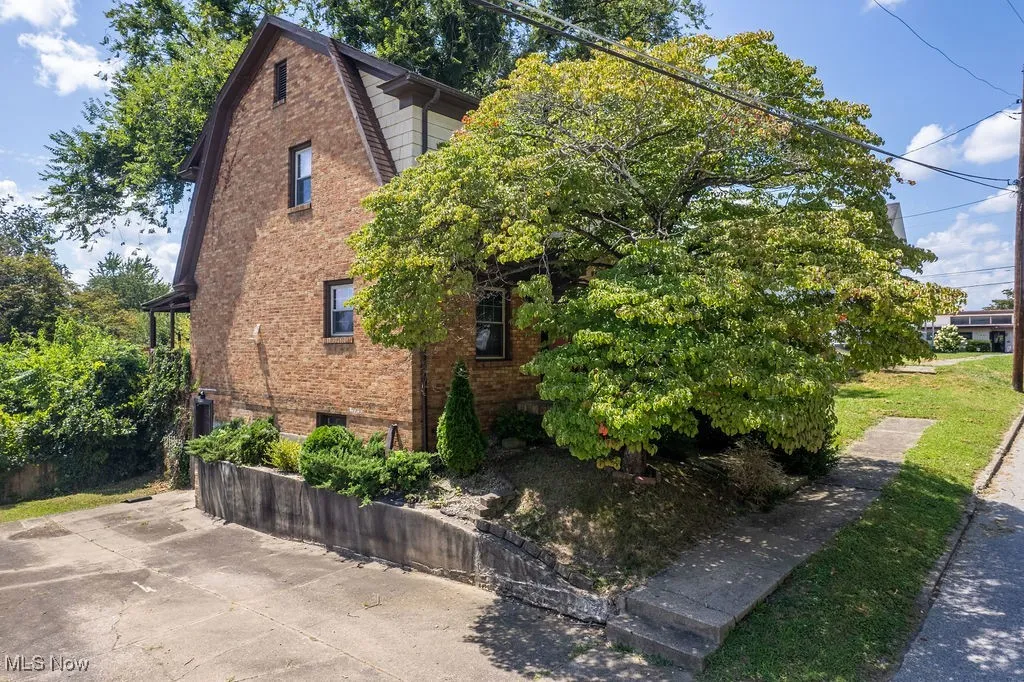 View of side of property featuring a gambrel roof and brick siding