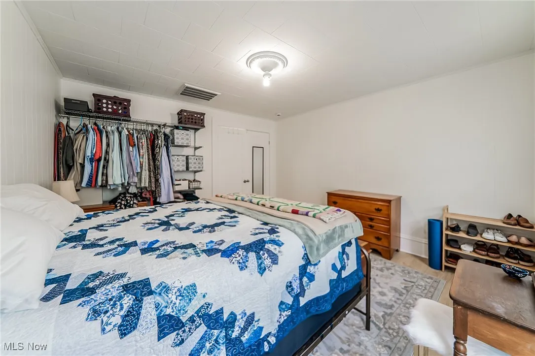 Bedroom featuring a closet, wood finished floors, and ornamental molding