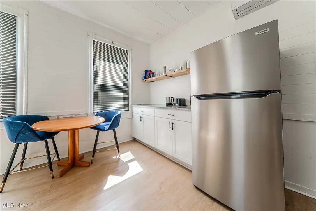 Kitchen featuring freestanding refrigerator, white cabinetry, open shelves, light wood-type flooring, and a wall unit AC