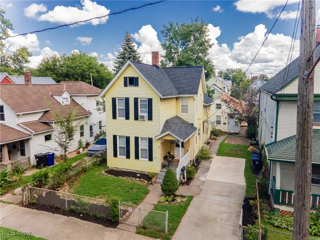 Traditional home featuring a fenced front yard, a chimney, a residential view, roof with shingles, and a gate