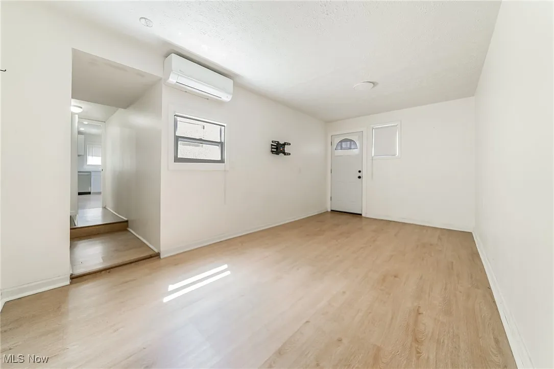 Entryway with an AC wall unit, light wood-style floors, and a textured ceiling