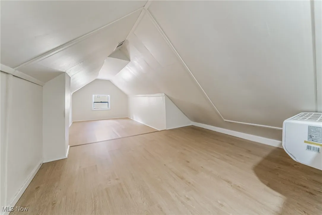Additional living space featuring light wood-style flooring and vaulted ceiling