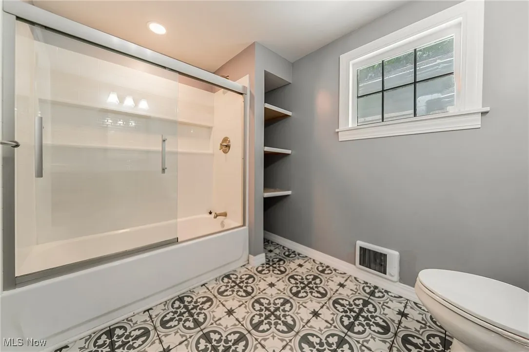Bathroom featuring shower / bath combination with glass door, tile patterned flooring, and recessed lighting