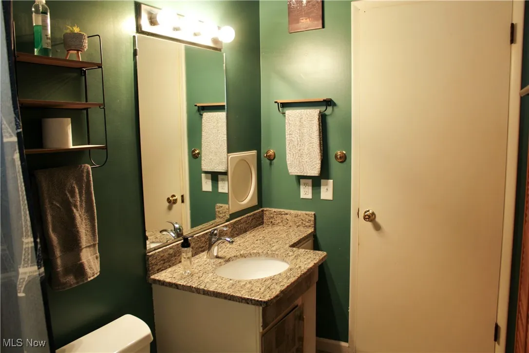 Bathroom with vanity, toilet, and laundry shoot