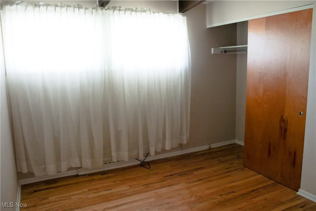 Bedroom with wood finished floors and closet