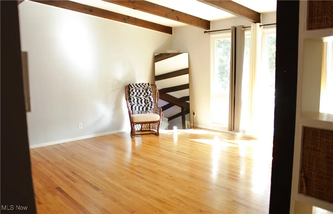 Living area with beam ceiling and wood finished floors