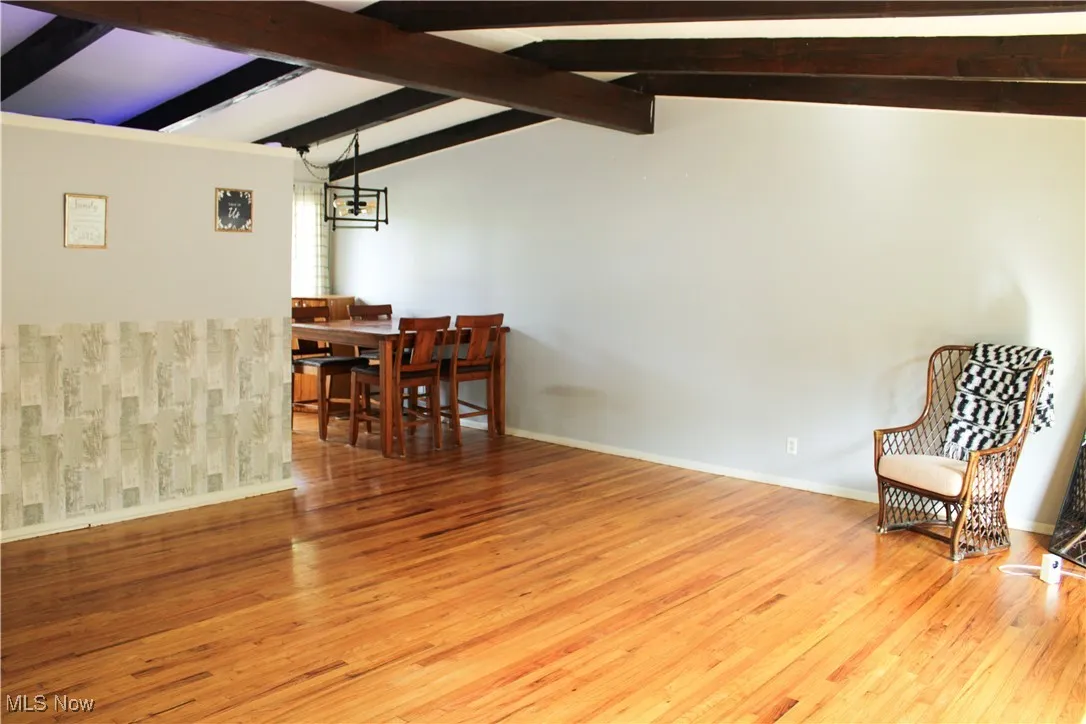 Living area with light wood-style flooring and beamed ceiling