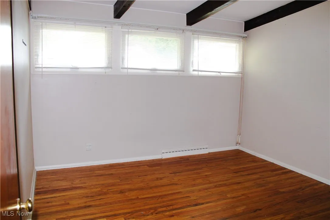 Master featuring wood finished floors and beam ceiling