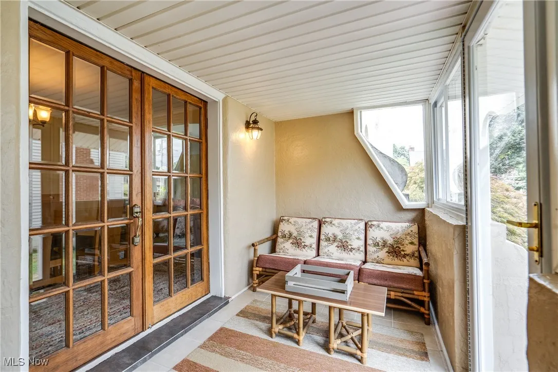 Sunroom / solarium with tile patterned floors, french doors, and a textured wall