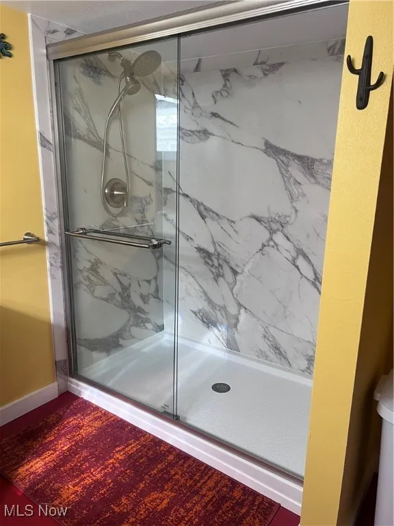 Full bath featuring a marble finish shower Basement