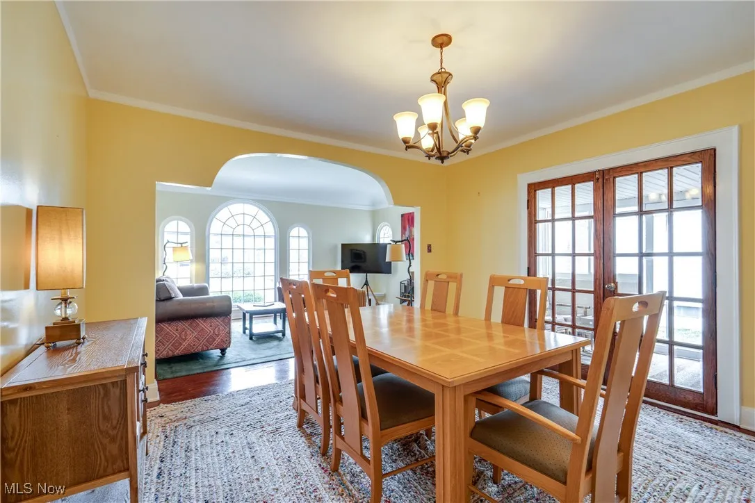 Dining area featuring ornamental molding, plenty of natural light, arched walkways, a chandelier, and wood finished floors