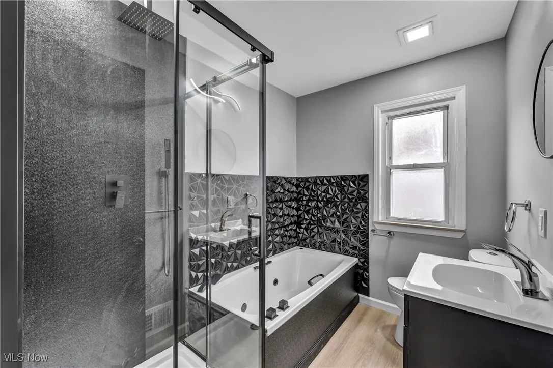 Full bath featuring a shower stall, vanity, a tub with jets, and light wood finished floors