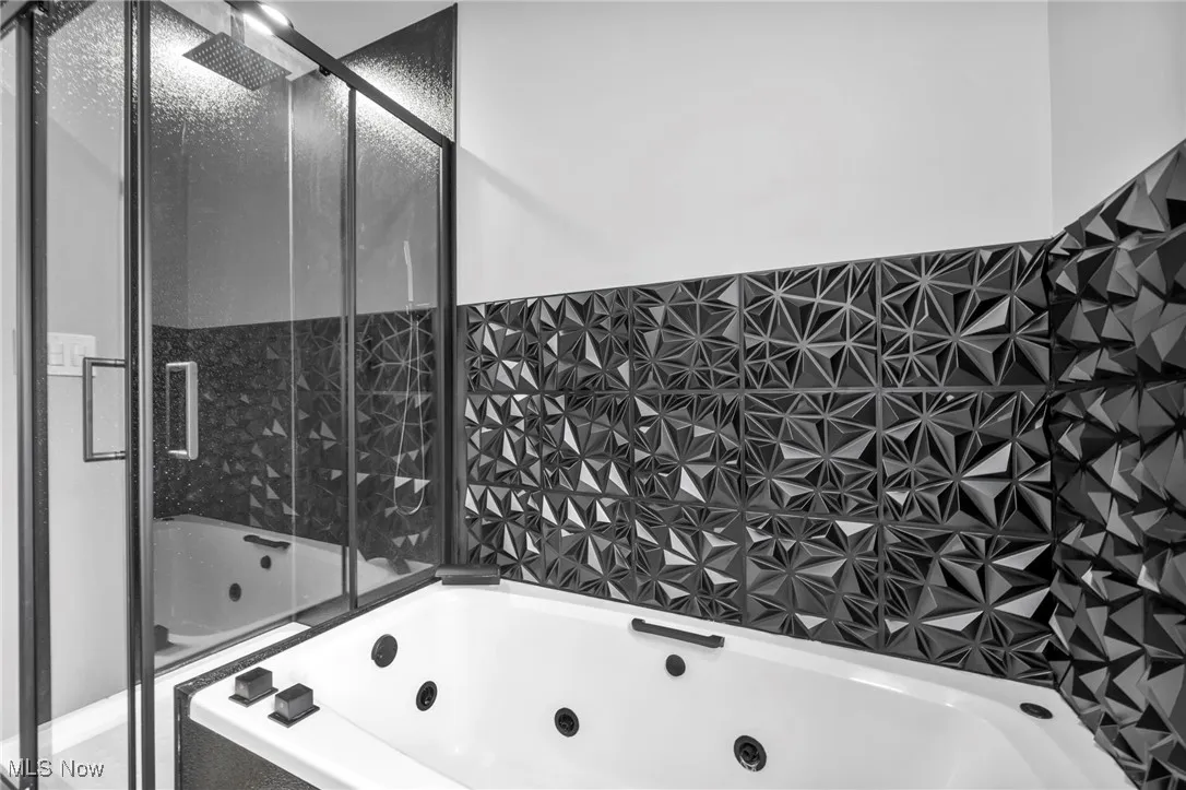 Full bath with a shower stall, a whirlpool tub, and tile walls