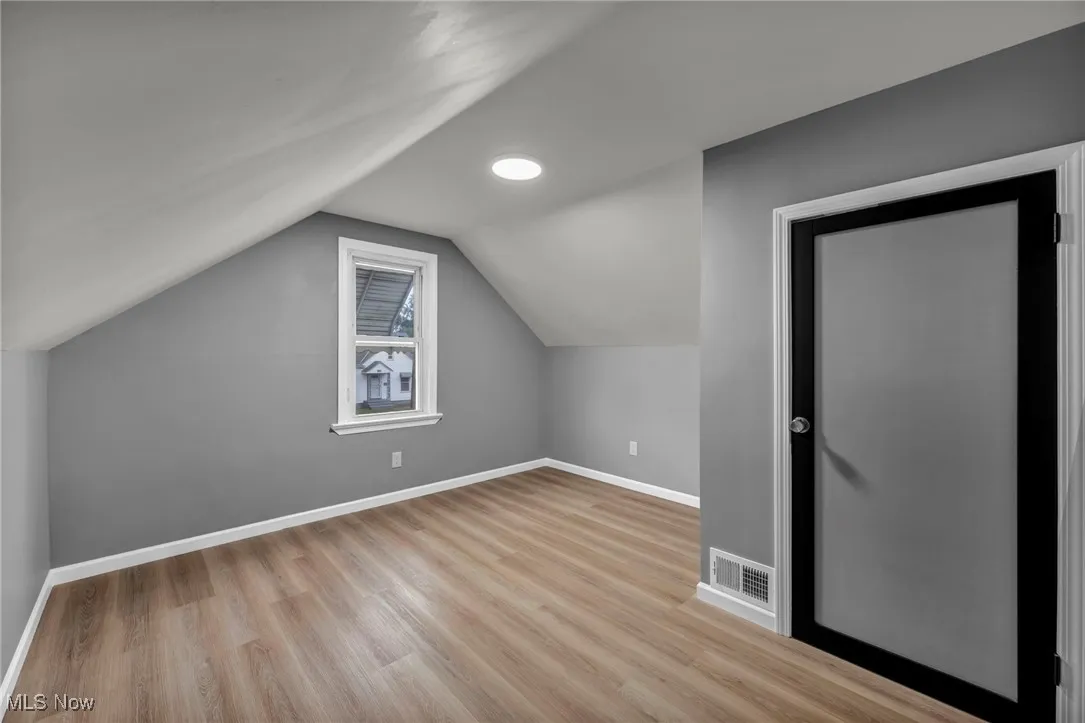Additional living space with vaulted ceiling and light wood-style floors