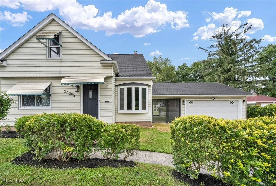 View of front of property featuring an attached garage, roof with shingles, and a front yard