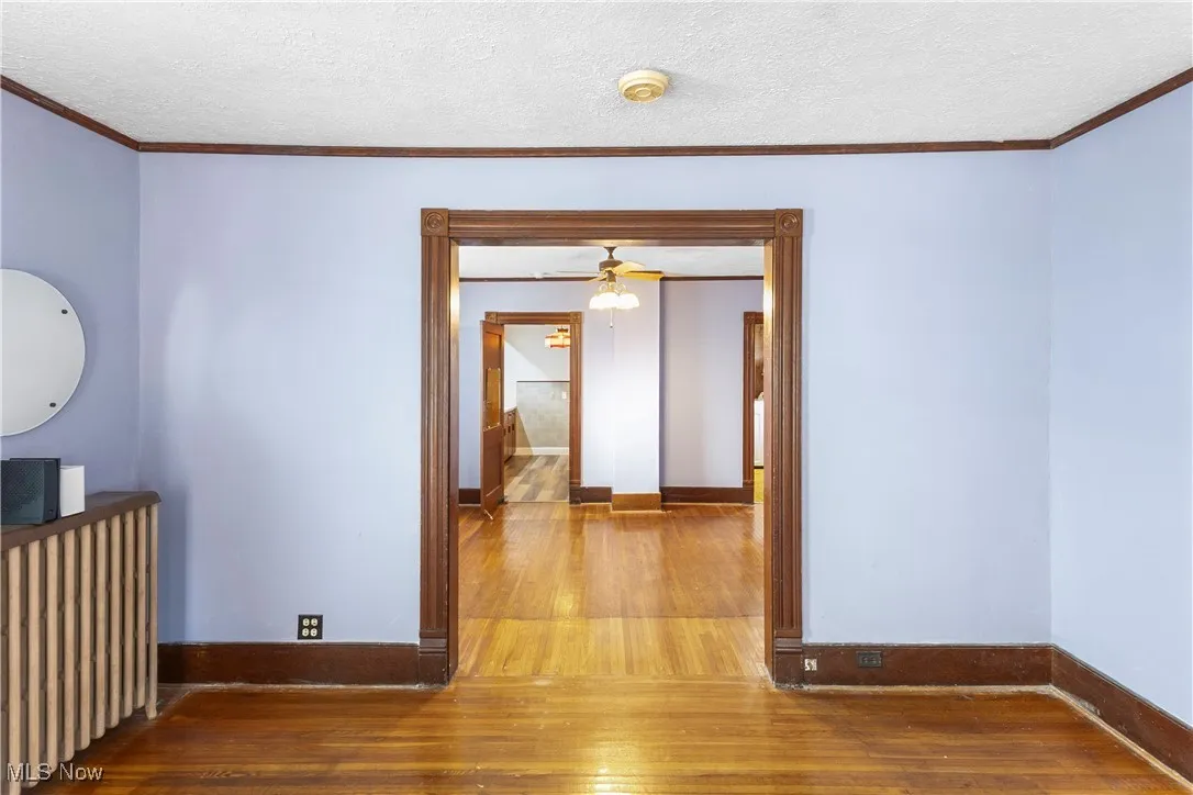 Unfurnished room with hardwood / wood-style floors, crown molding, a textured ceiling, radiator, and ceiling fan