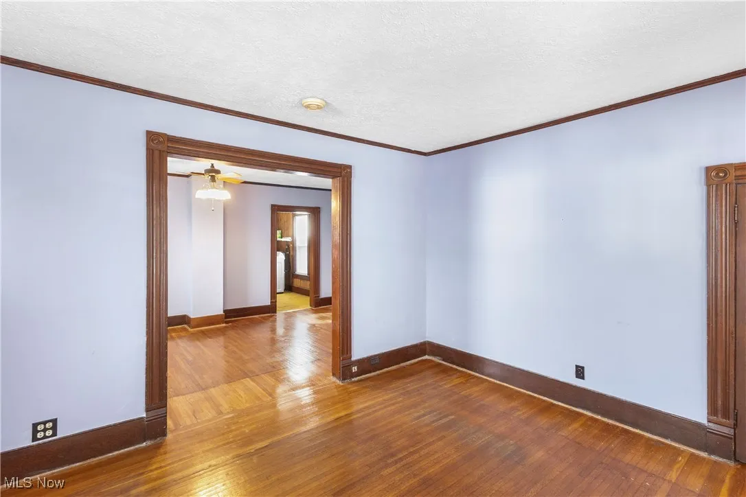 Empty room with ornamental molding, dark wood finished floors, and a textured ceiling