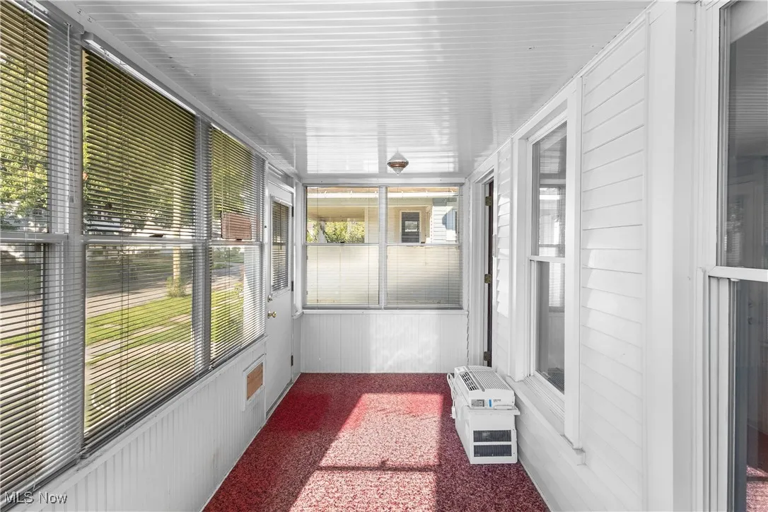 Unfurnished sunroom with carpet and wooden walls