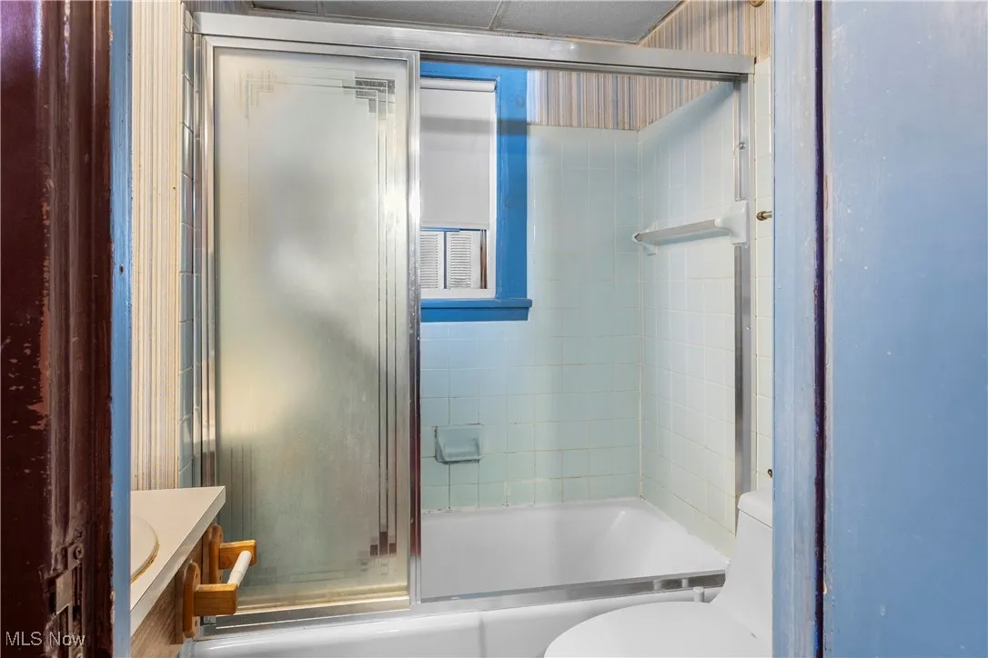 Full bathroom with enclosed tub / shower combo and vanity