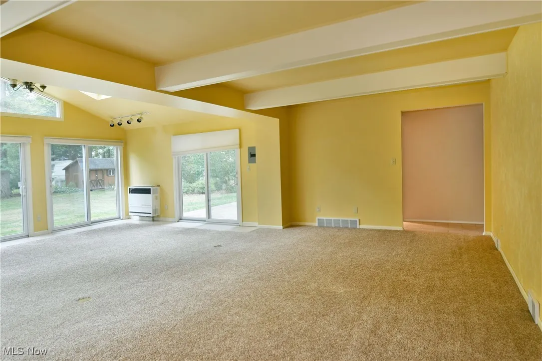 Unfurnished living room featuring carpet flooring and heating unit