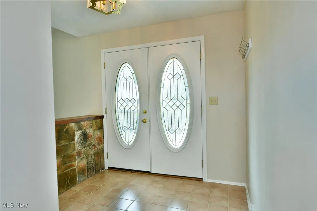 Foyer featuring french doors, light tile patterned floors, and a chandelier