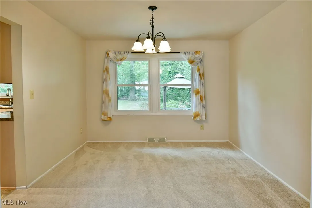Unfurnished dining area featuring carpet floors and a chandelier