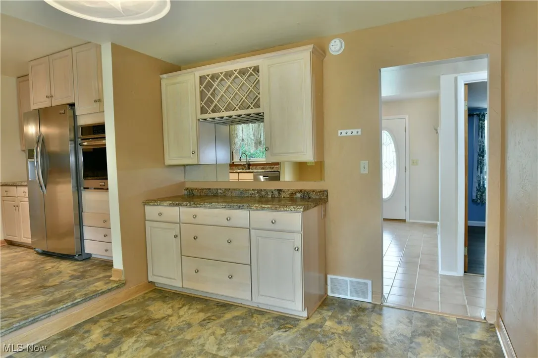 Kitchen featuring stainless steel appliances, dark stone counters, and light tile patterned flooring