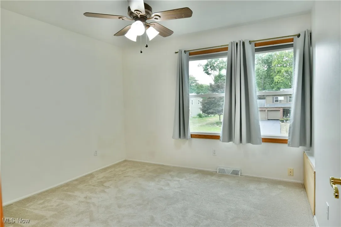 Carpeted spare room featuring ceiling fan and baseboards