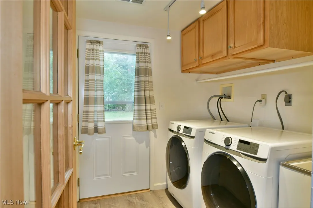 Washroom featuring independent washer and dryer, cabinet space, and light wood-style floors