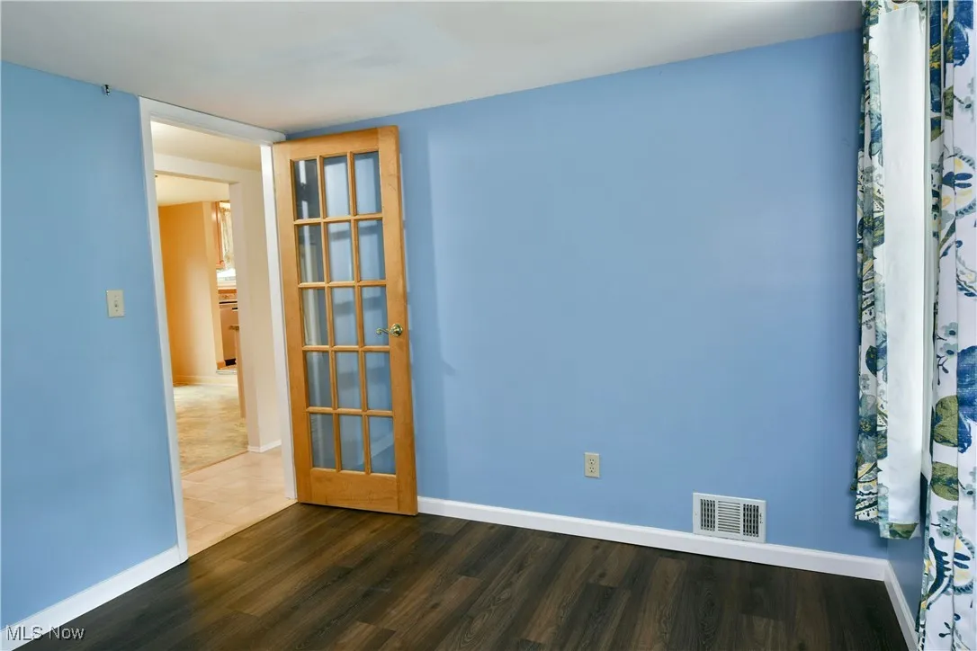Unfurnished room featuring baseboards and dark wood-style floors
