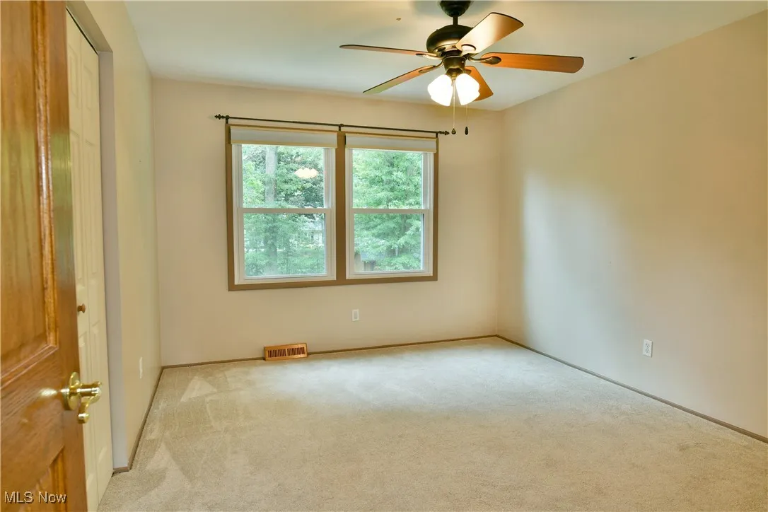 Carpeted spare room featuring a ceiling fan and baseboards
