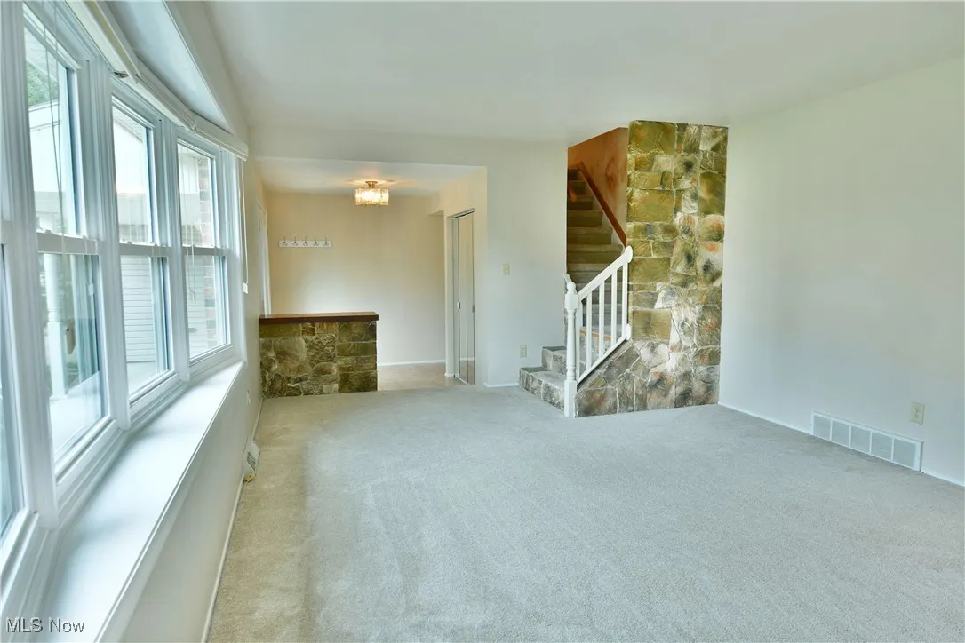 Empty room with light colored carpet and stairway