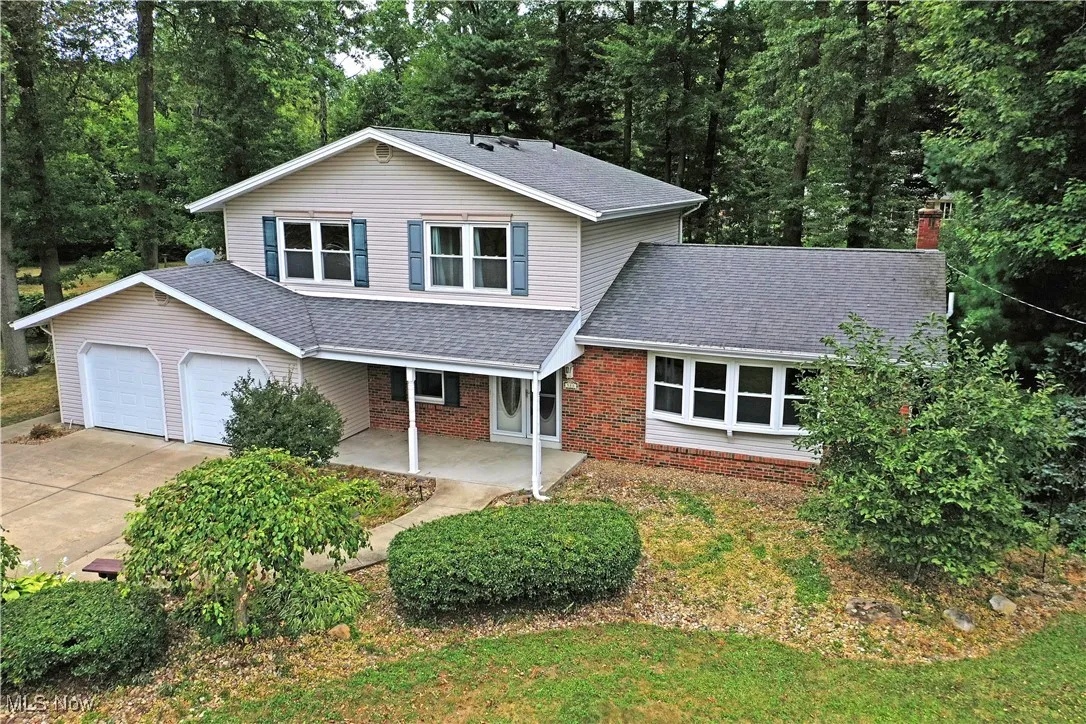 Traditional-style home with roof with shingles, a porch, brick siding, and concrete driveway