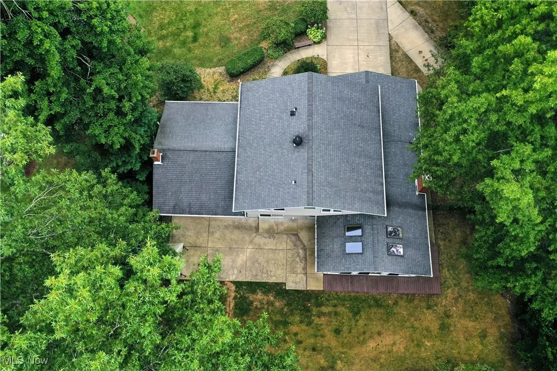 Aerial view of property and surrounding area with a tree filled landscape