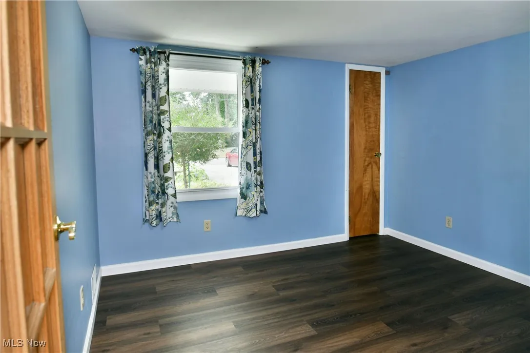Empty room with dark wood-style flooring and baseboards