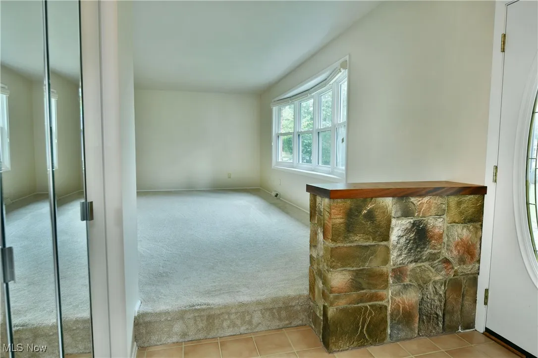 Unfurnished room featuring light carpet and light tile patterned floors