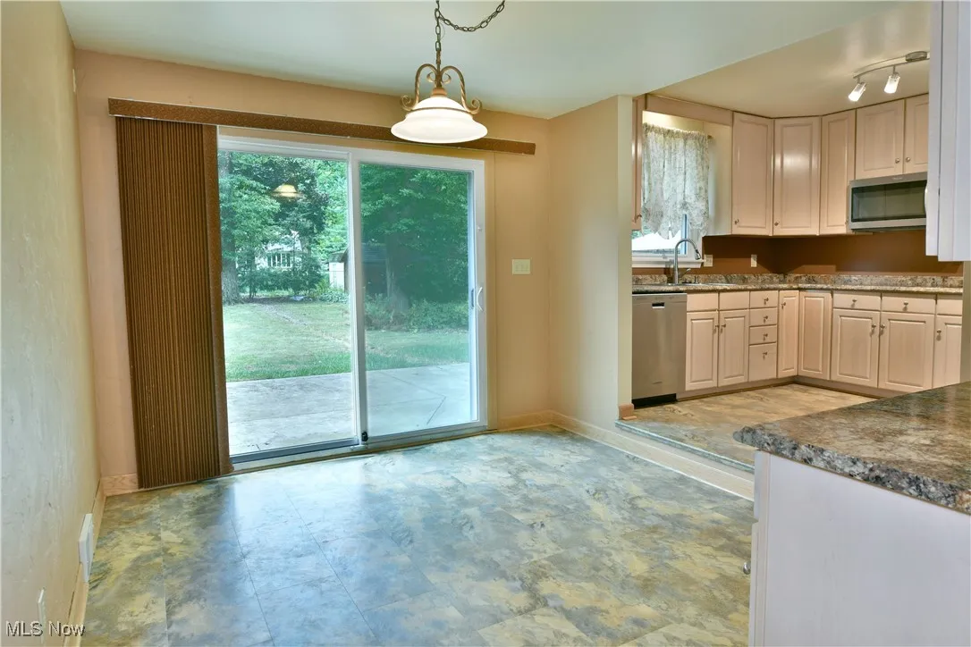 Kitchen featuring decorative light fixtures, stainless steel appliances, and dark stone counters