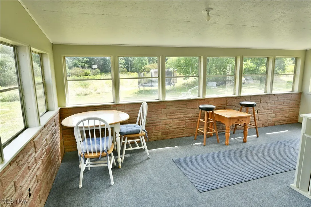 Sunroom / solarium with brick wall, carpet, and a textured ceiling