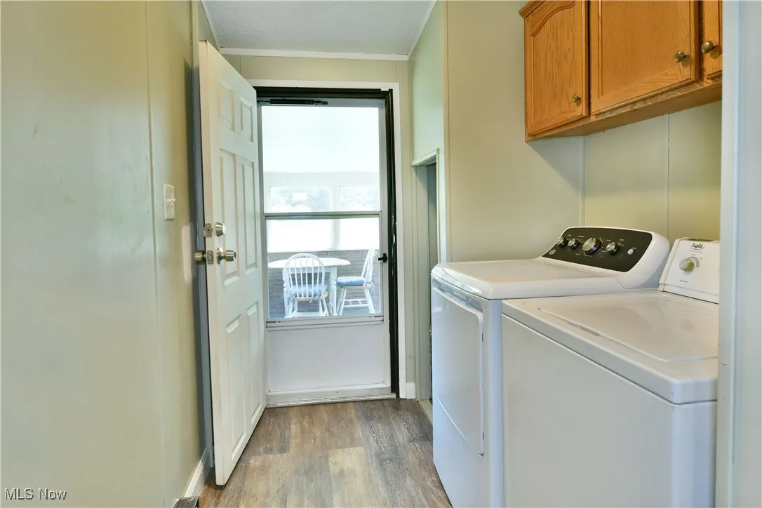 Washroom featuring light wood finished floors, independent washer and dryer, and cabinet space