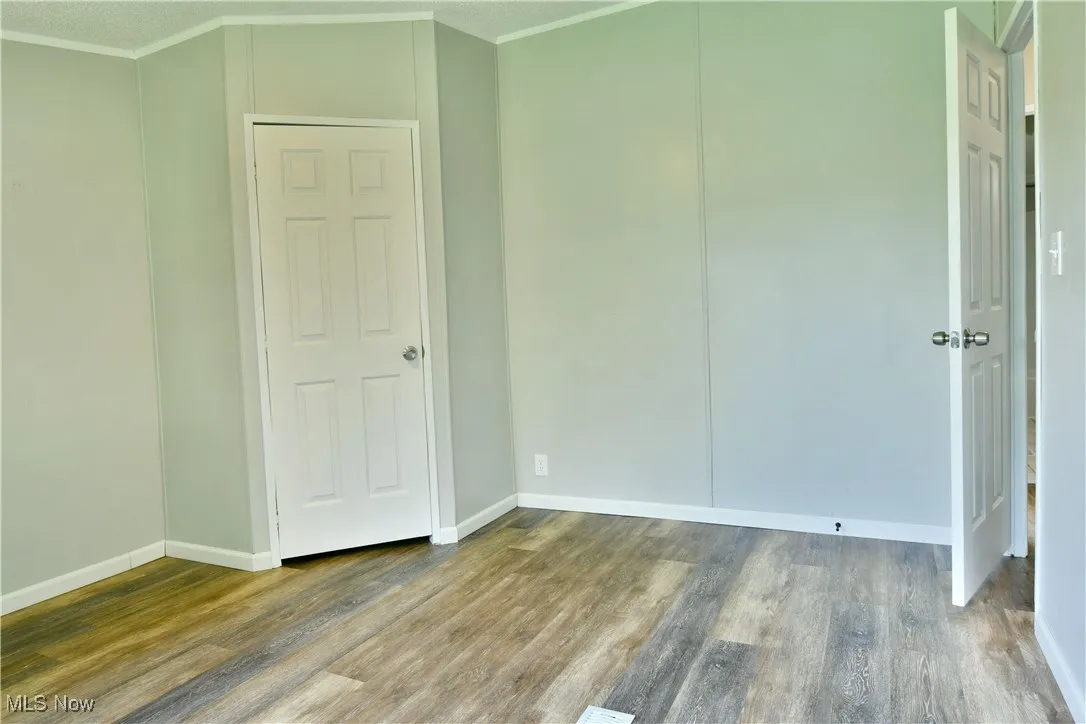 Unfurnished bedroom with wood finished floors and crown molding