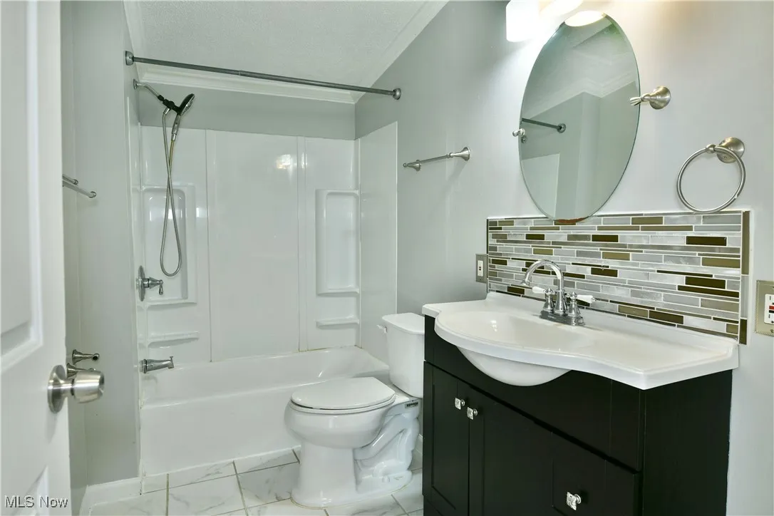 Bathroom with tasteful backsplash, shower / tub combination, vanity, light marble finish flooring, and a textured ceiling