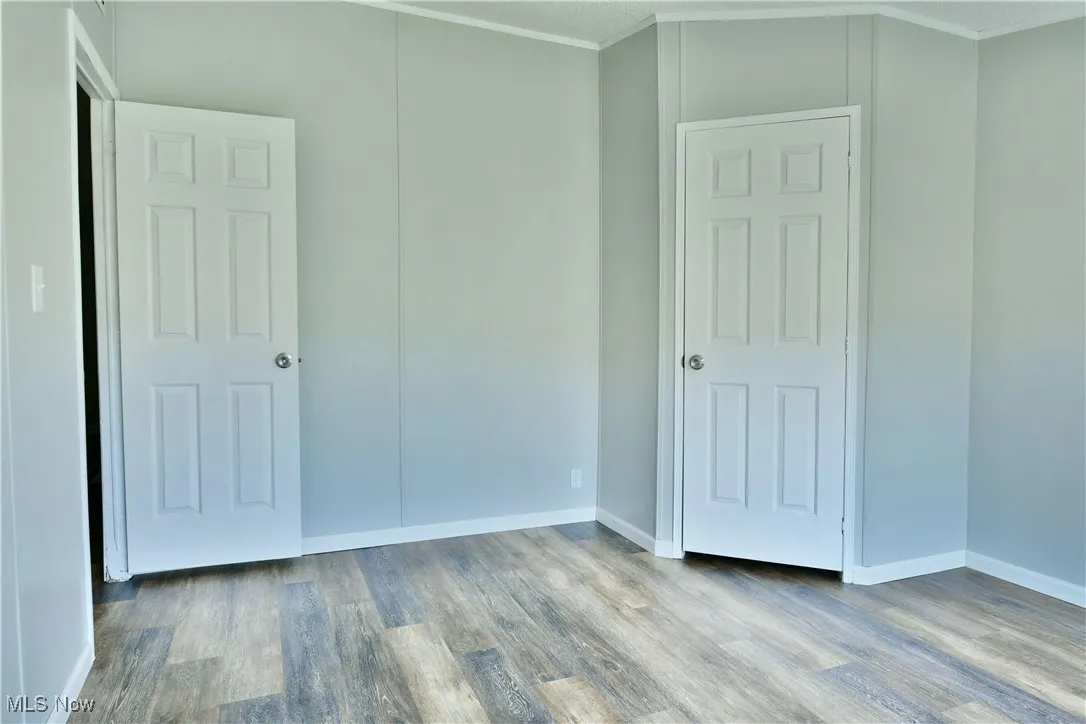 Unfurnished bedroom featuring wood finished floors and crown molding