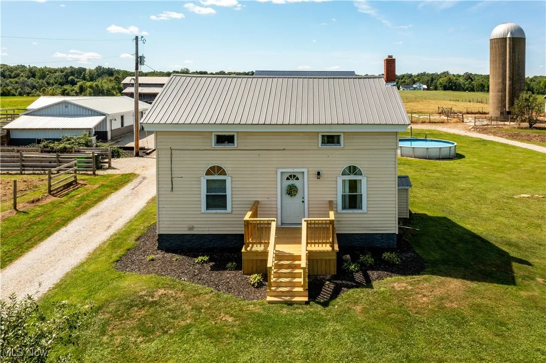 View of front of property with a rural view, a metal roof, a front lawn, an outdoor pool, and a chimney