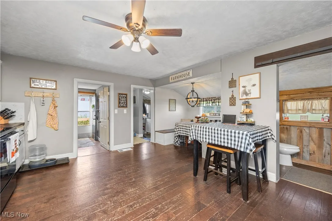 Dining area featuring dark wood-style flooring, ceiling fan, and a textured ceiling