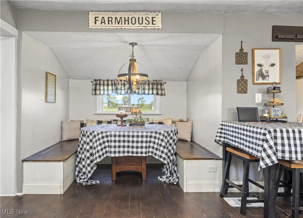 Dining area featuring vaulted ceiling, dark wood-style floors, and breakfast area