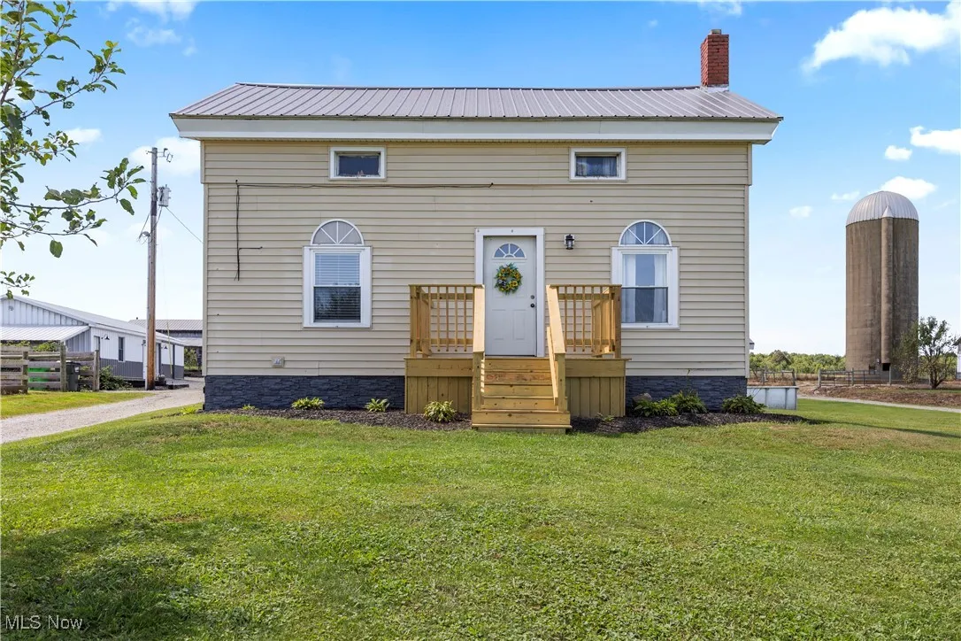 View of front of home with a metal roof, a front lawn, and a chimney