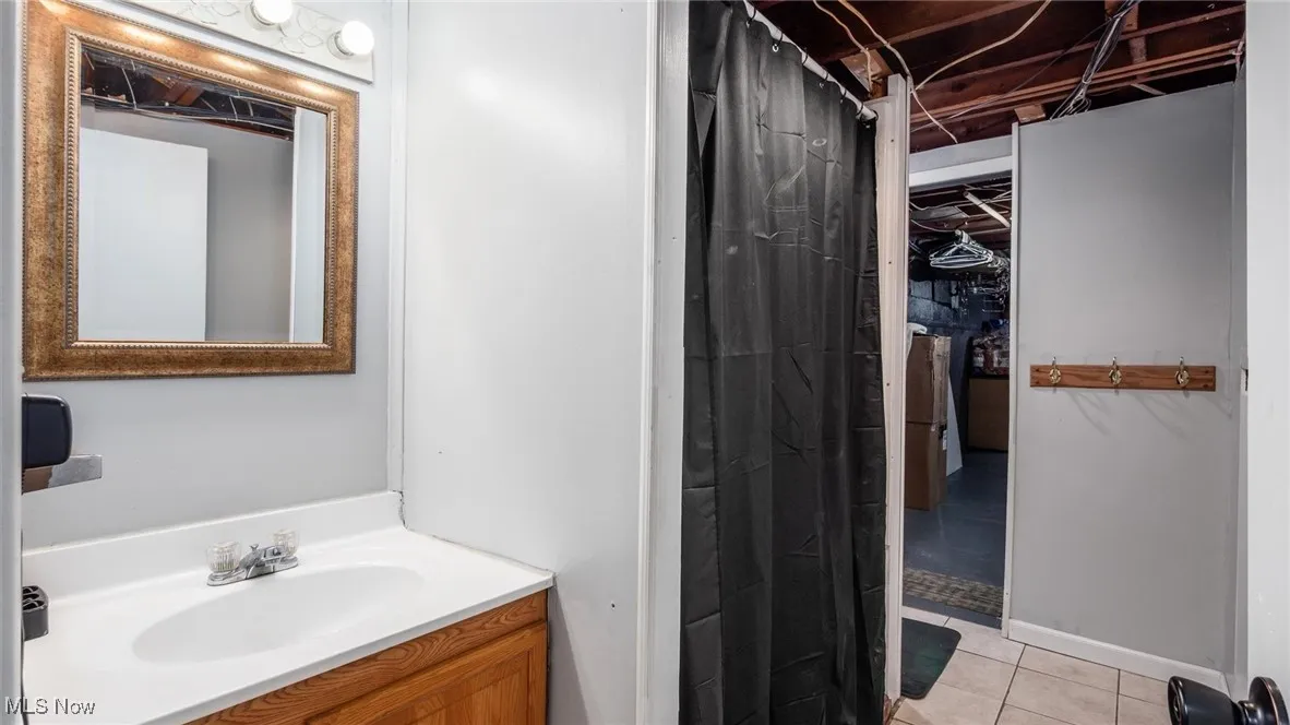 Full bathroom with vanity, light tile patterned flooring, and a shower with curtain